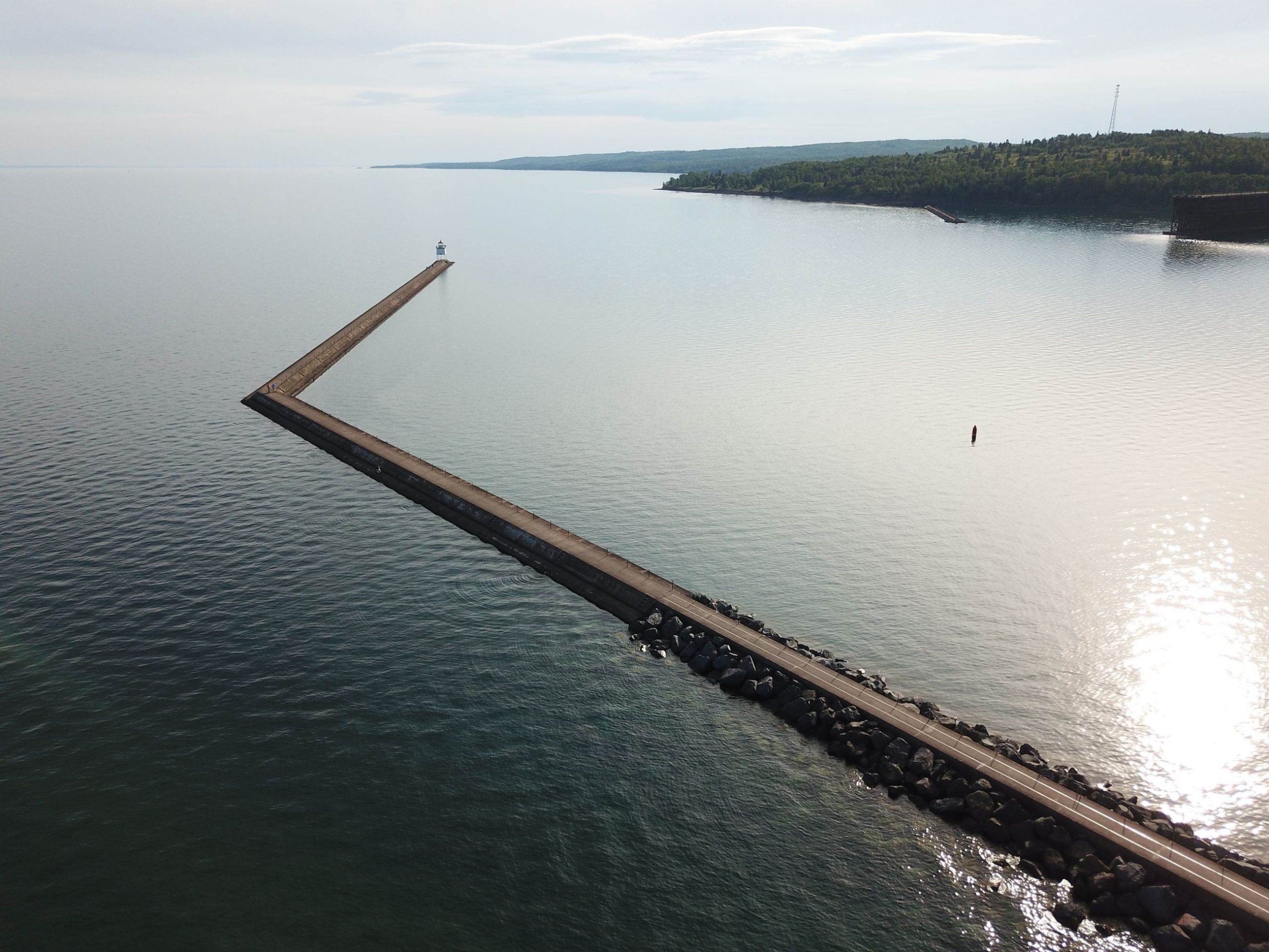 A stone breakwater reaching into calm open water in early morning light