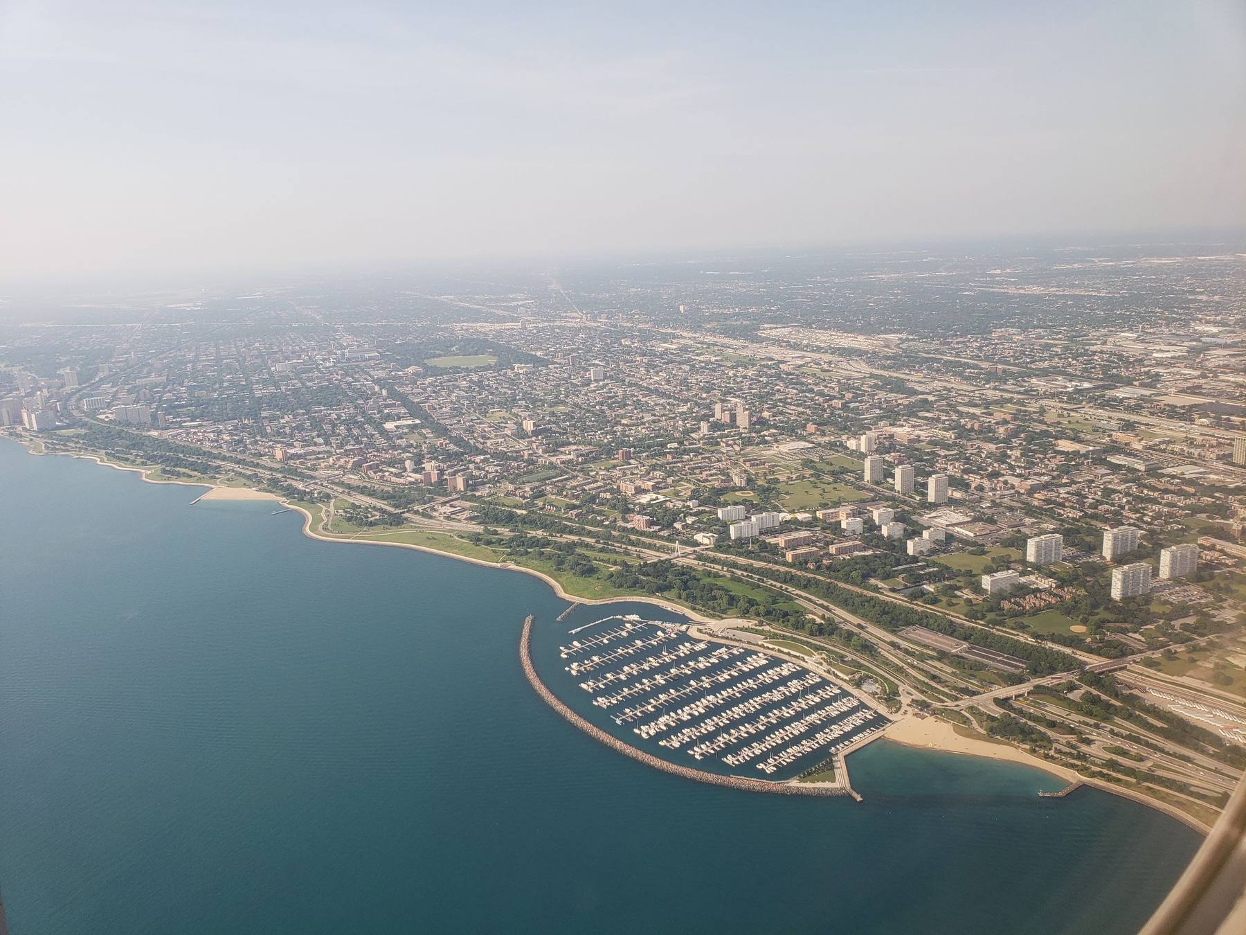 Aerial view of a lakefront city with a marina and breakwater